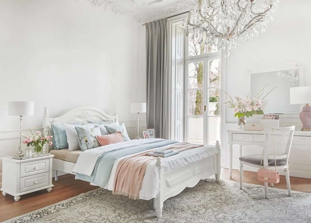 Stylowe, białe łóżko sypialniane Caroline, dostępne wymiary 140x200, 160x200 i 180x200. Rama frezowana, zagłówek ze sztukaterią, w rogach tralki.