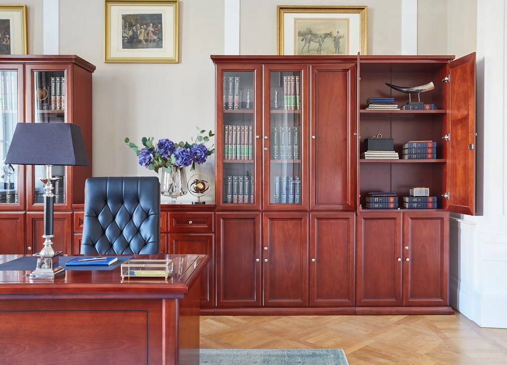 Elegancka szafa do biura Diamante. Szafa ma pełne drzwi, zamki na kluczyk, fronty wykończone płyciną, półki o regulowanej wysokości. Jest elegancko fornirowana na kolor koniaku, ma piękny cokół i gzyms.