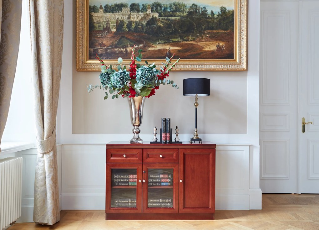 Elegancka klasyczna komoda do gabinetu Elegance. Komoda jest 3-drzwiowa, ma 2 drzwi przeszklonych, 2 szuflady. Komoda jest fornirowana, fronty wykończone płyciną. Funkcjonalna komoda biurowa.