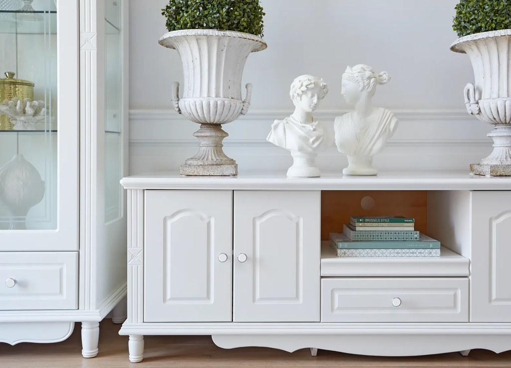 Stylowa biała szafka pod telewizor Sybilla 180x58x62 cm. Komoda rtv z podwójnymi drzwiami, półką i szufladą, delikatne zdobienia. Angielski styl, białe meble.