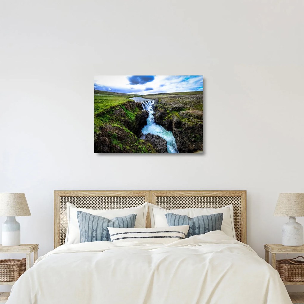 Obraz na szkle wodospadu między skałami (70x50 cm)