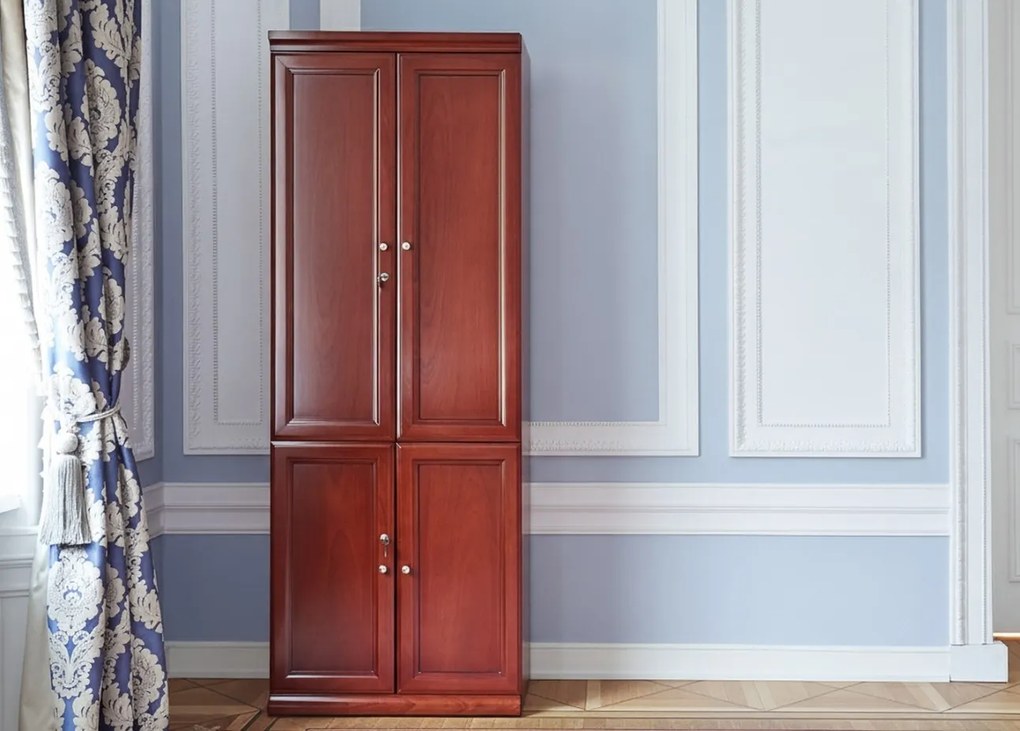 Elegancka szafa do biura Diamante. Szafa ma pełne drzwi, zamki na kluczyk, fronty wykończone płyciną, półki o regulowanej wysokości. Jest elegancko fornirowana na kolor koniaku, ma piękny cokół i gzyms.