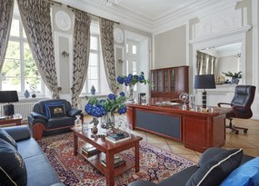 Biurko gabinetowe w kształcie litery L z szufladami i szafką. Biurko jest fornirowane, ma front i blat wykończony skórzaną wstawką, w blacie znajdują się przelotki. Do biurka są zamocowane kontener z szufladami i szafka.