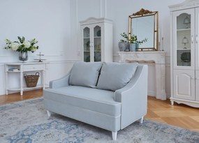 Kanapa sofa dwuosobowa do salonu. Sofa na drewnianych nóżkach, tapicerowana tkaniną welwetową. Sofa ma eleganckie podłokietniki, krawędzie obszyte kedrą, niebieska lub beżowa.