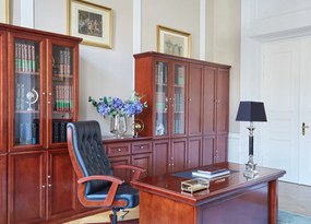 Elegancka szafa do biura Diamante. Szafa ma pełne drzwi, zamki na kluczyk, fronty wykończone płyciną, półki o regulowanej wysokości. Jest elegancko fornirowana na kolor koniaku, ma piękny cokół i gzyms.