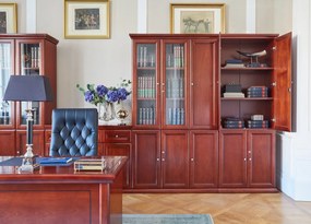 Elegancka szafa do biura Diamante. Szafa ma pełne drzwi, zamki na kluczyk, fronty wykończone płyciną, półki o regulowanej wysokości. Jest elegancko fornirowana na kolor koniaku, ma piękny cokół i gzyms.