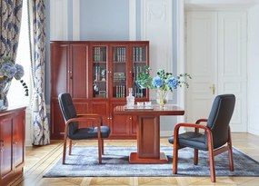 Elegancki stolik biurowy Visitor fornirowany drewnem w odcieniu koniaku. Stolik ma wymiary 100x100x75 cm. Kwadratowy blat na kolumnie zdobionej płycinami, rant frezowany. Klasyczny stolik do gabinetu.